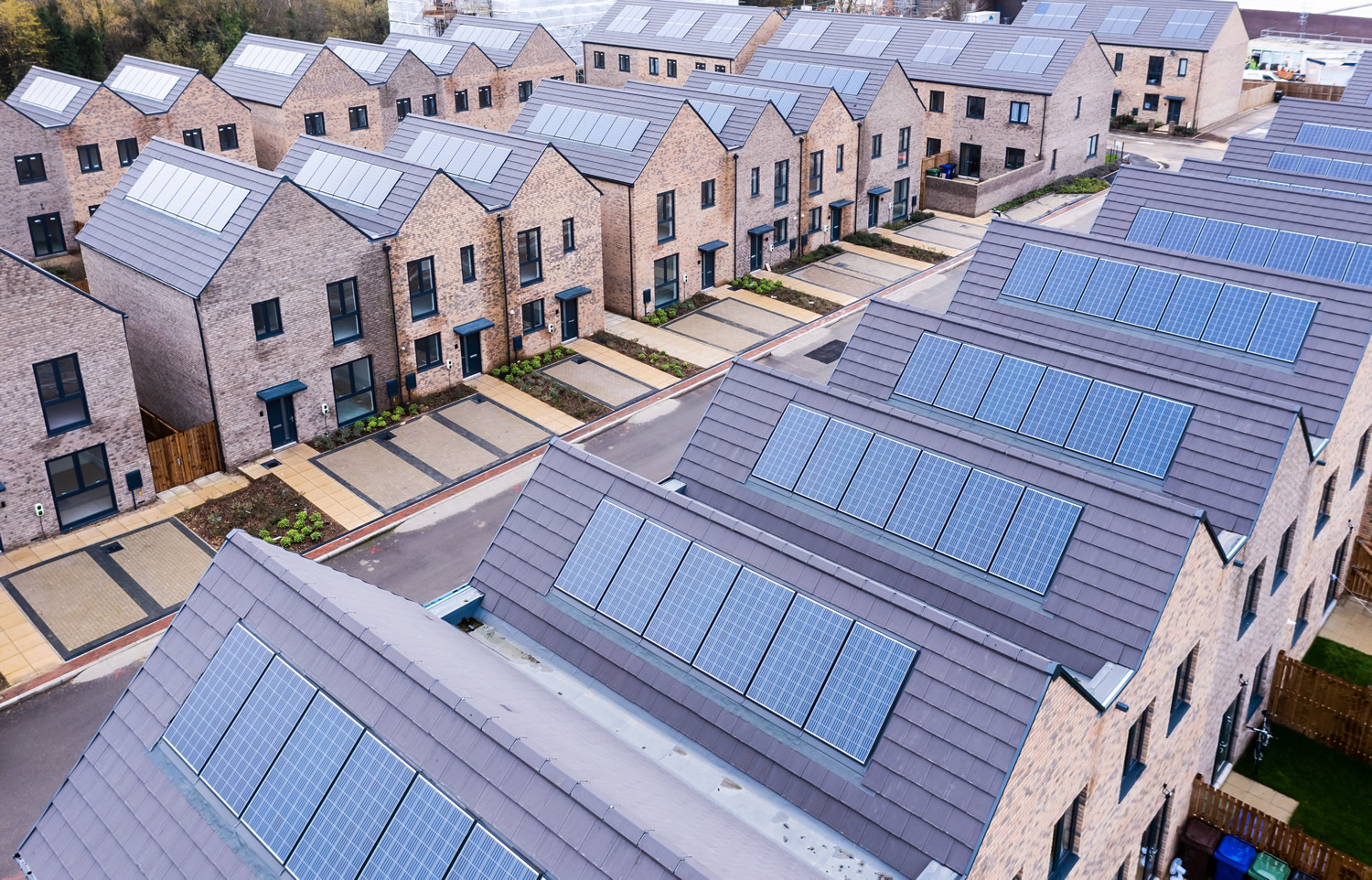 Aerial view of rows of energy efficient new build modular terraced houses in the UK with characterless design and in built rooftop solar panels for first time buyers 